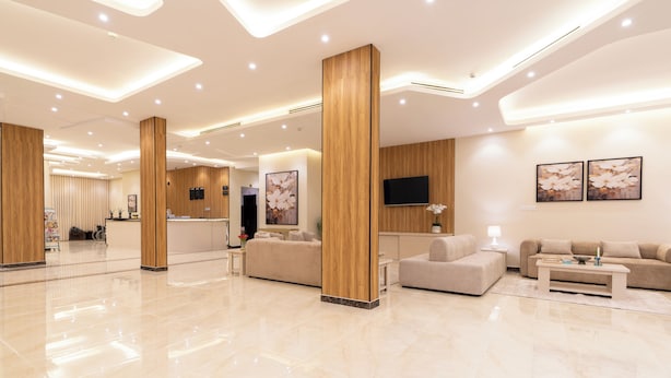 A modern hotel lobby with a reception desk, sofas, a coffee table, and artwork on the walls. - Deyala Serviced Apartments 6 (Riyadh)