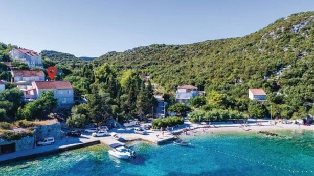 Ein Küstendorf mit klarem türkisblauem Wasser, Booten und Häusern mit roten Dächern.