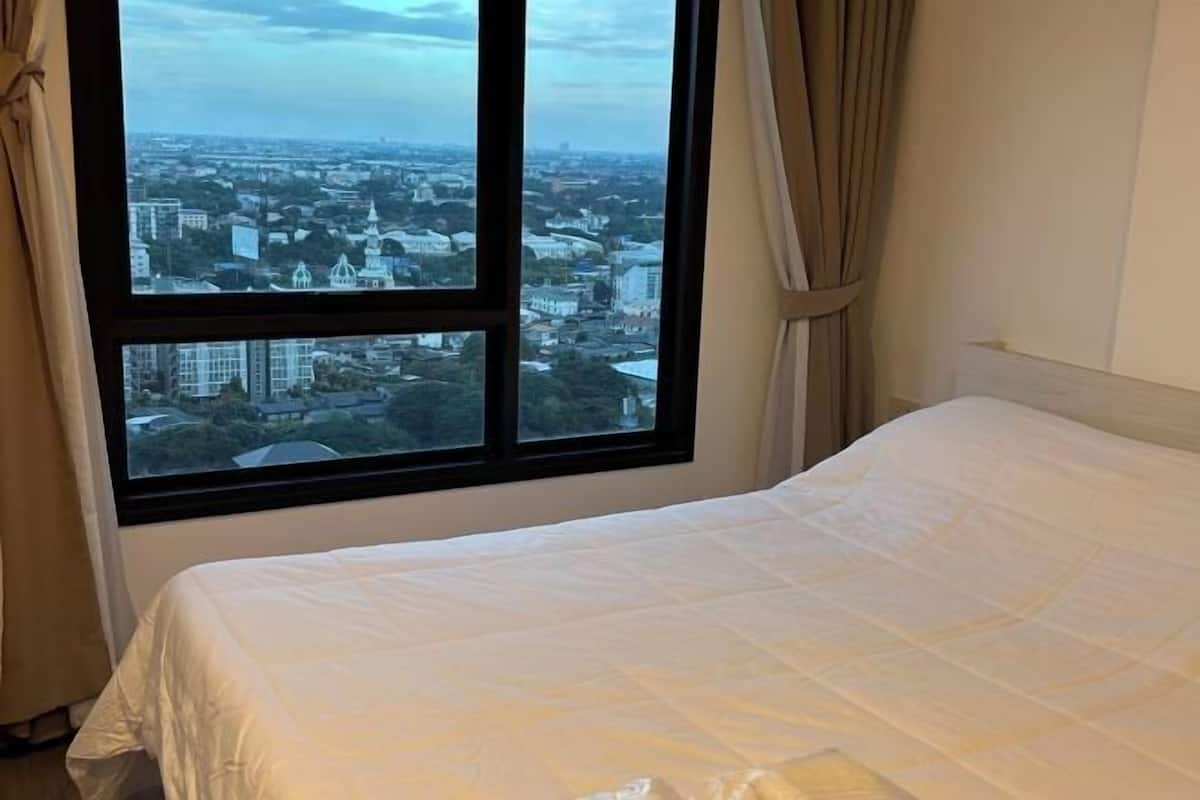 Habitación de hotel con cama y ventana grande que ofrece vista a la ciudad.