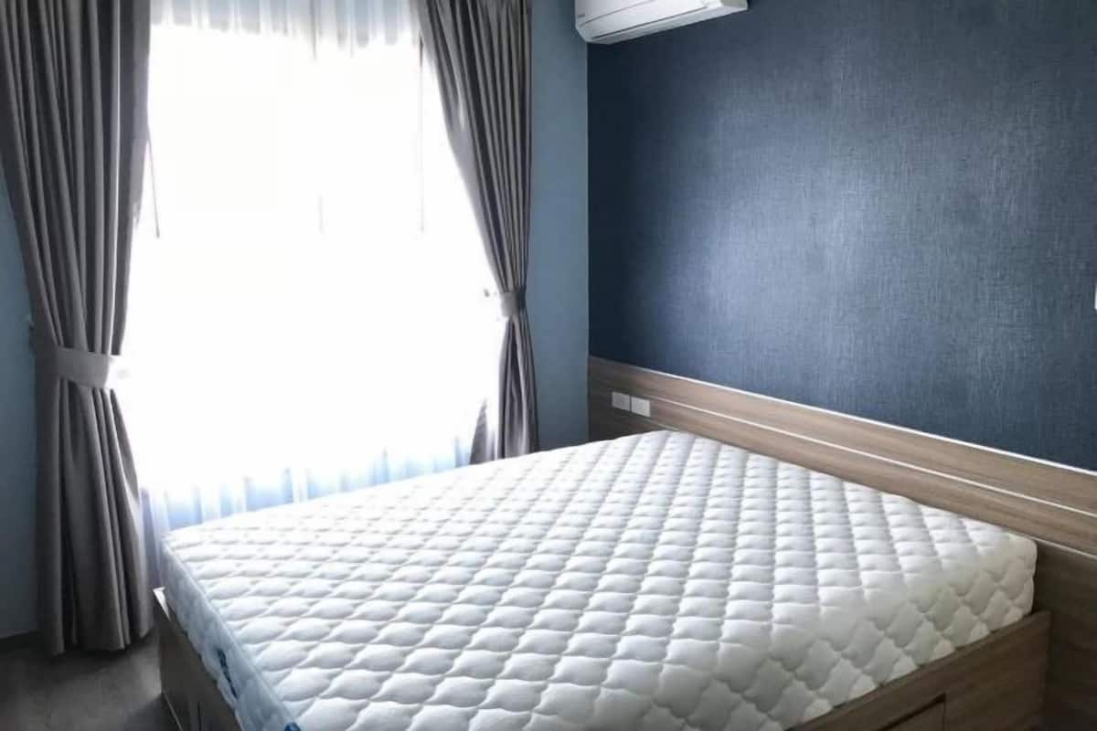 Habitación de hotel con cama, cortinas y aire acondicionado.