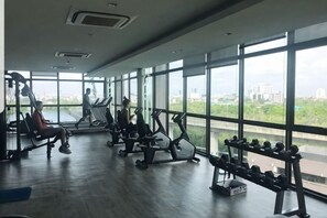 A gym with exercise equipment, large windows, and a view of the city.