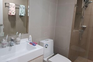 Un bany amb un lavabo, mirall, vàter i plat de dutxa.
