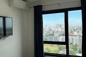 Una habitación con un ventanal grande, un televisor de pantalla plana en la pared y un equipo de aire acondicionado.