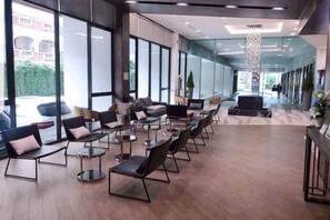 Een moderne hotelentree met een rij zitplaatsen, grote ramen en een centraal sierlicht.
