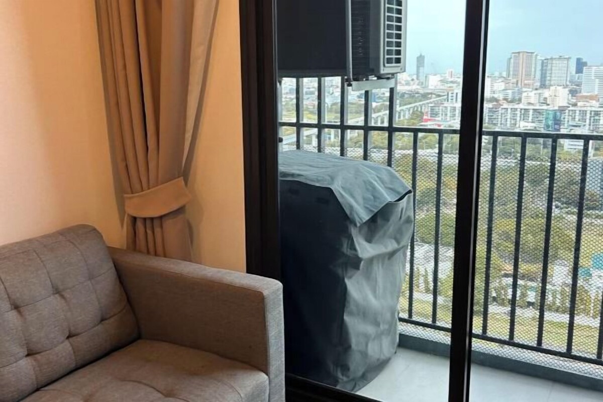 Habitación con sofá, cortina, televisor y balcón con vista a la ciudad.