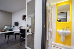 A modern bathroom with a yellow accent wall, a white sink, and a glass shower enclosure. - Student Only Sycamore House (Leeds)