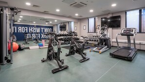 Uma academia com equipamentos de cardio, pesos e um espelho grande.
