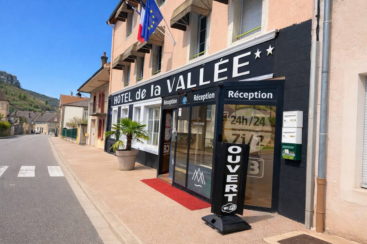 Un hotel llamado HOTEL de la VALLEE con áreas de recepción y un letrero que indica servicio las 24 horas.