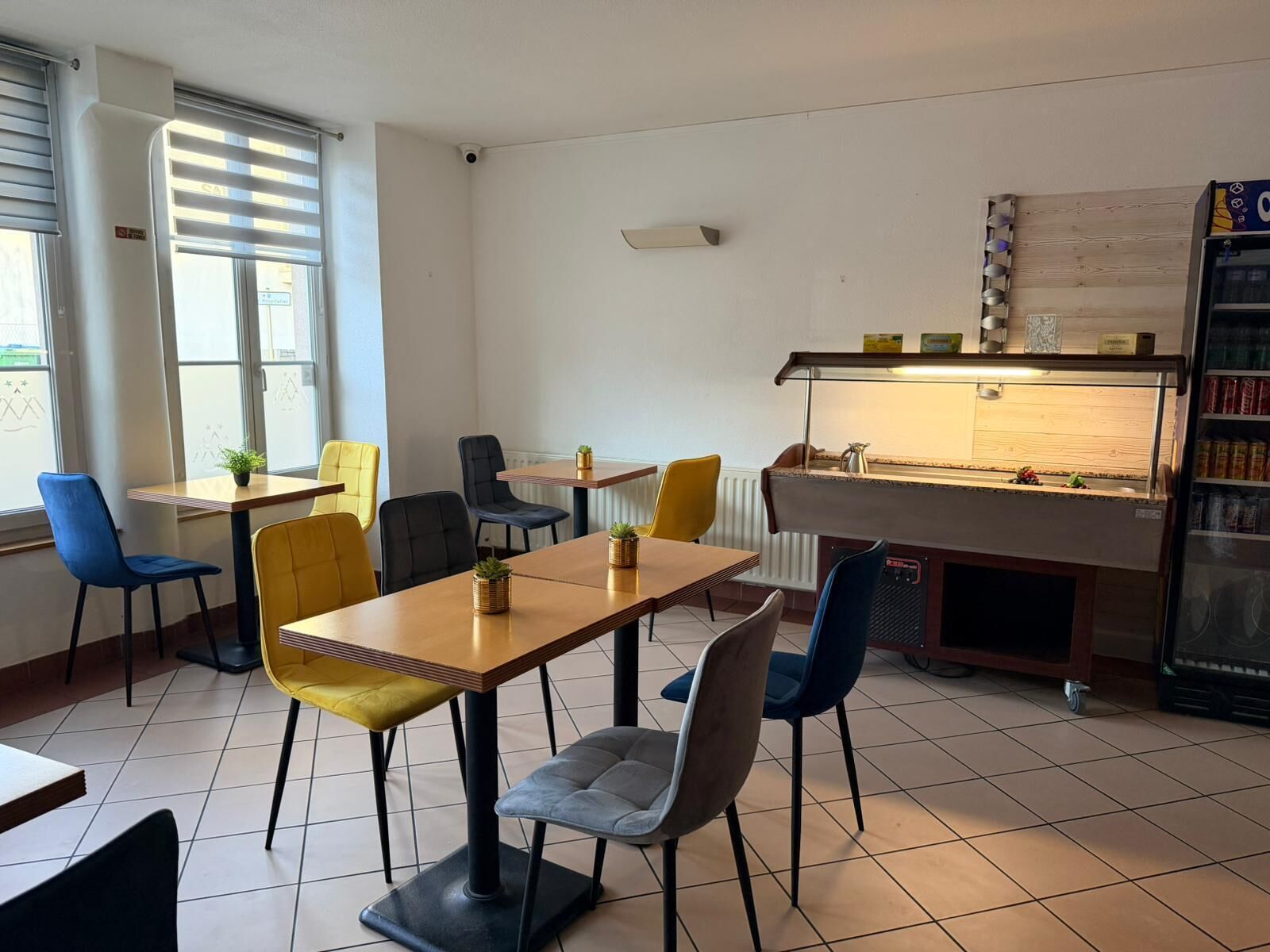 A restaurant with a wooden table and chairs, a counter with a display case, and a vending machine.