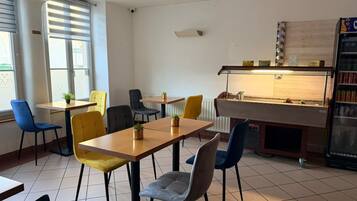A restaurant with a wooden table and chairs, a counter with a display case, and a vending machine.