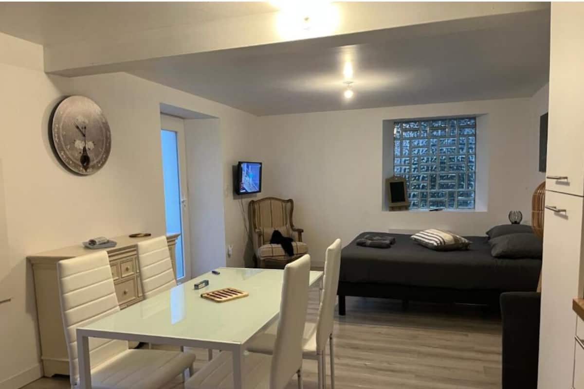 Un espacio habitable compacto con comedor, cama, televisión y ventana con vista a un paisaje urbano.