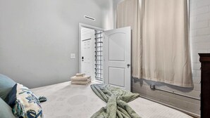 Ein Schlafzimmer mit Bett, einem Fenster mit Vorhängen, einer Tür zu einem Kleiderschrank und einer Heizung.