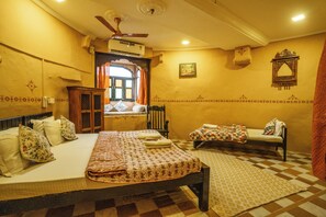 Une chambre traditionnelle avec un lit, une armoire en bois, une fenêtre avec des rideaux, un climatiseur fixé au mur et un tapis à motifs.