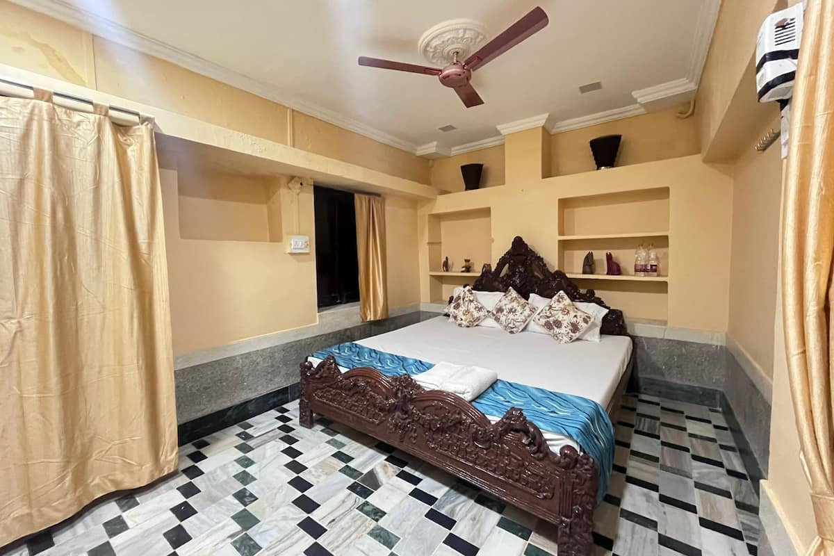 A bedroom with a bed, a ceiling fan, a checkered floor, and a wardrobe.