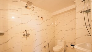 Baño con paredes de mármol, inodoro, lavabo y ducha.