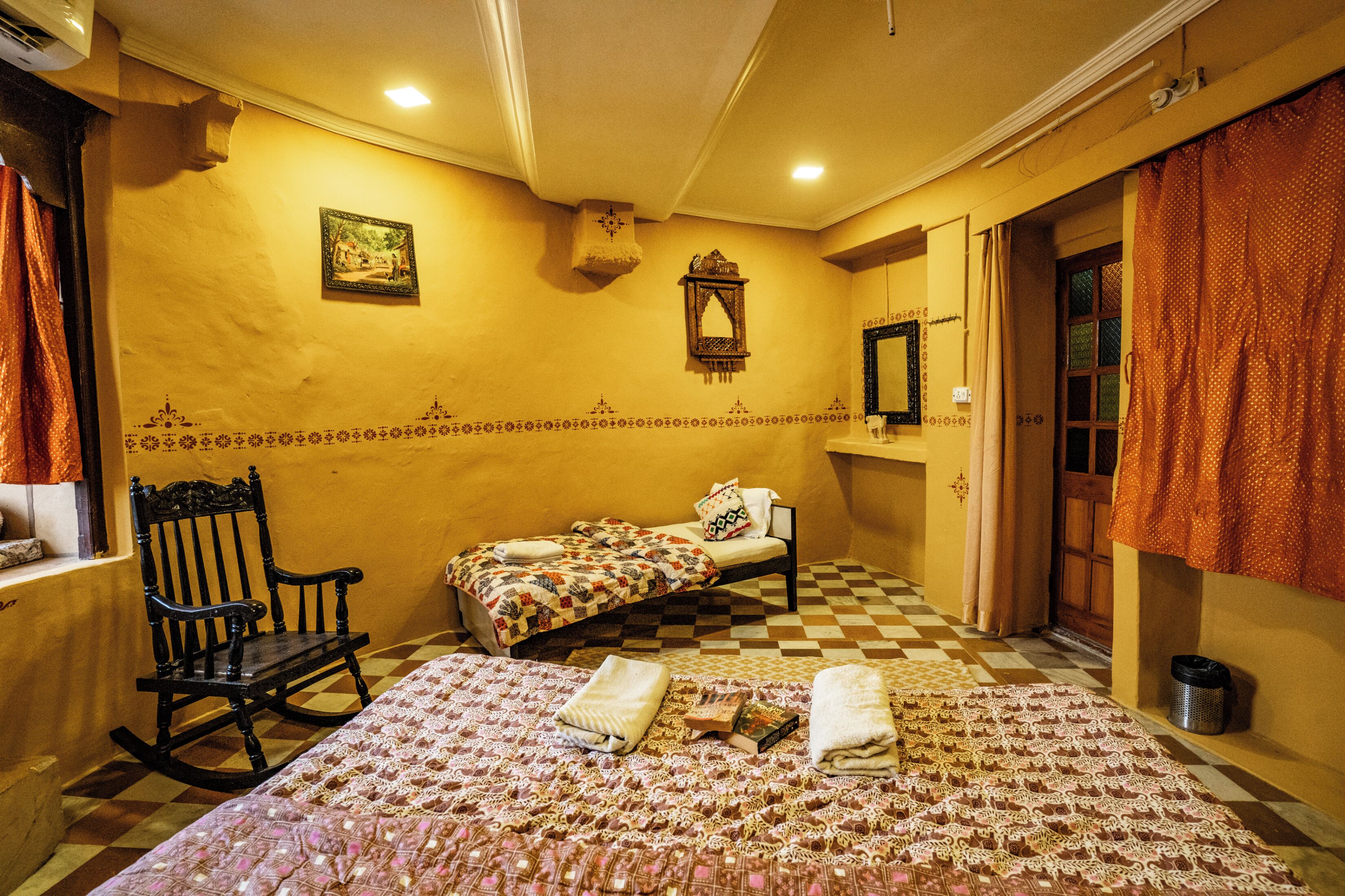 Une chambre d’hôtel avec deux lits, une chaise, un miroir et un tableau au mur.