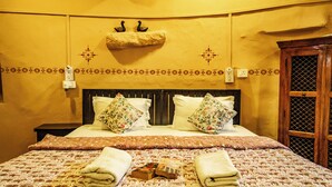Habitación de hotel con cama, dos almohadas, mesita de noche, interruptor de luz en la pared, un adorno en la pared y una ventana con marco de madera.
