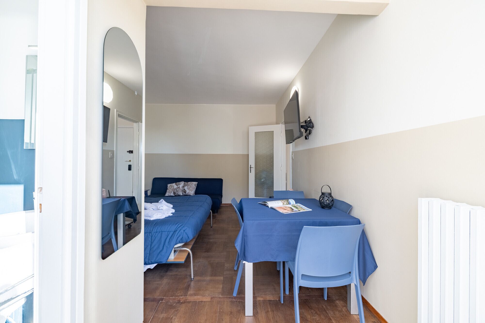 A compact room with two single beds, a table with a chair, and a mirror on the wall.
