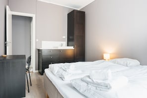 A hotel room with a bed, a desk, a chair, a wardrobe, and a bedside lamp. - S54 - Private Rooms in the city center (Bergen)