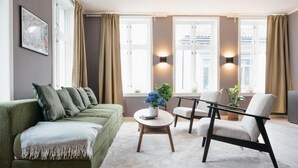 Een moderne woonkamer met een groene bank, een ronde salontafel en een witte fauteuil.