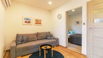 Ein modernes Wohnzimmer mit einem grauen Sofa, einem runden Couchtisch und zwei gerahmten Bildern an der Wand.