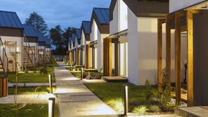 A row of modern, single-story buildings with a uniform design, featuring large windows and a flat roof. - Baltic Natur Park - Family Resort  (Niechorze)