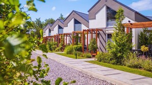 A row of modern, two-story buildings with large windows and a well-maintained garden area. - Baltic Natur Park - Family Resort  (Niechorze)