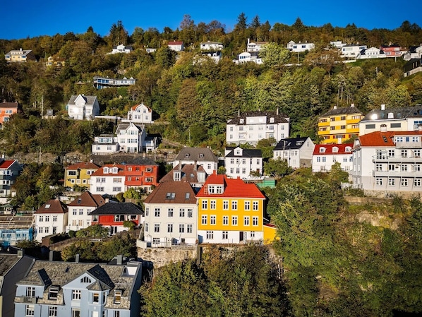 Un quartier résidentiel situé sur une colline, avec des maisons aux couleurs vives, dont certaines ont des toits rouges, et qui présente un mélange de styles architecturaux.