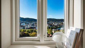 A room with a large window offering a view of a cityscape and mountains.