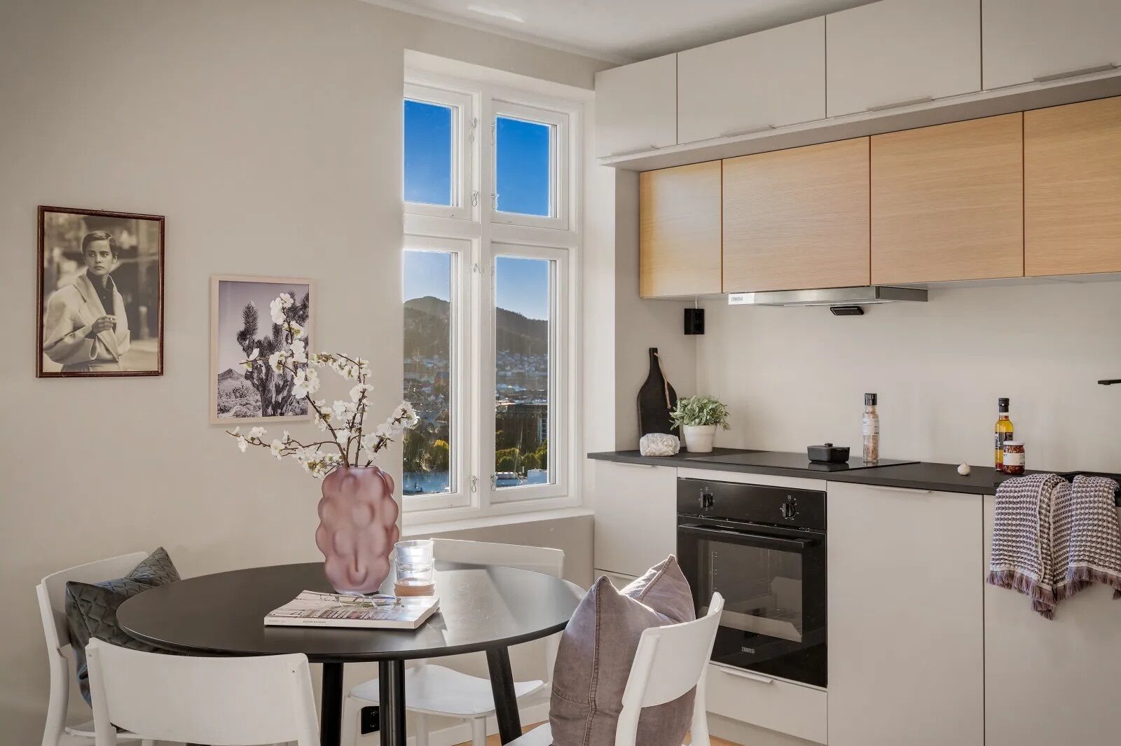 Een moderne keuken met witte kasten, een zwart aanrecht en een groot raam met uitzicht.