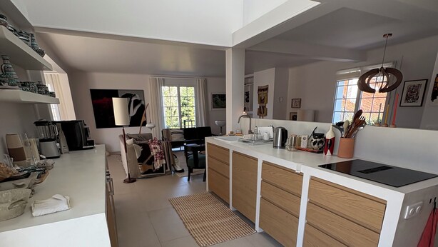 Una cocina moderna con armarios blancos, estufa integrada y comedor con mesa y sillas.