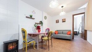 A cozy living room with a fireplace, a dining table, and a sofa. - Tropical Garden (Lower 2) (Granada)