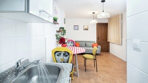 A modern kitchen with a sink, a dining area with a table and chairs, and a sofa. - Tropical Garden (Lower 2) (Granada)