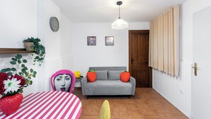 A living room with a grey sofa, a striped table, and a wall clock. - Tropical Garden (Lower 2) (Granada)