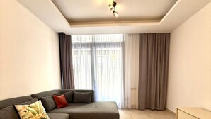 En moderne stue med en hjørnesofa, et gulvtæppe med geometriske mønstre og et minimalistisk skab.
