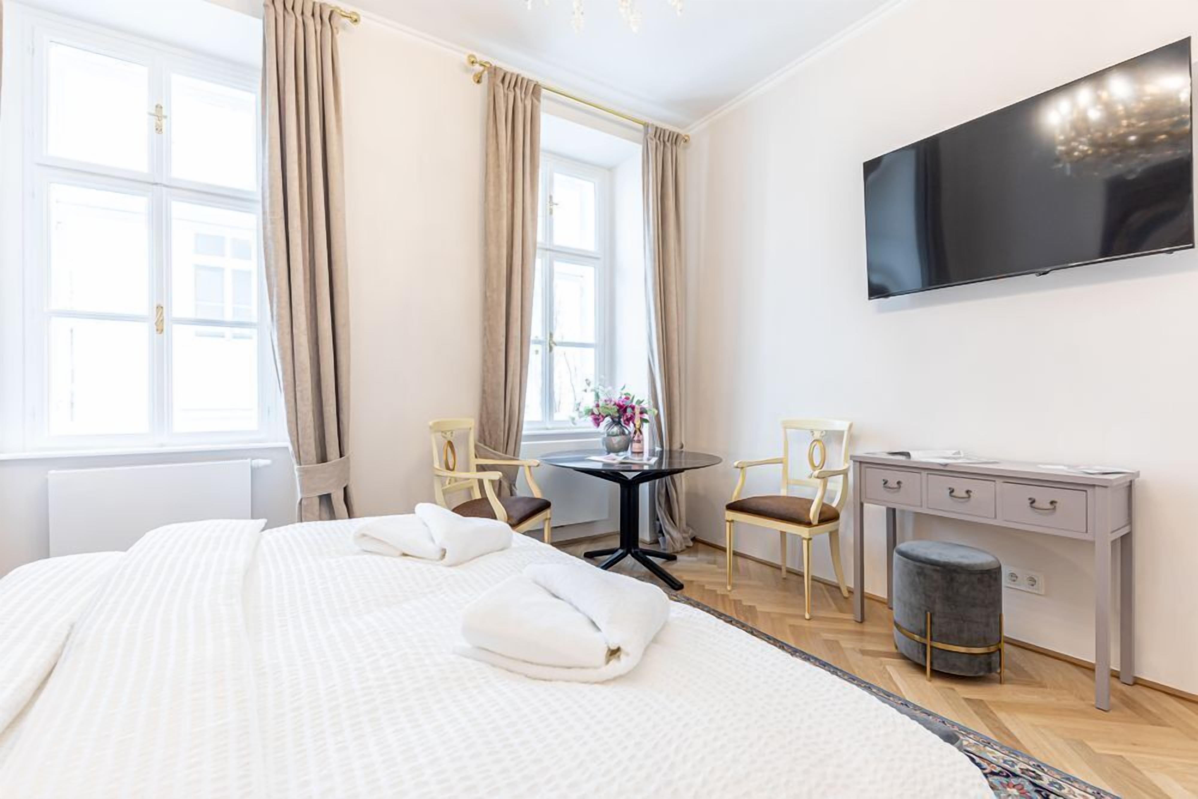 Habitación de hotel con una cama grande, un escritorio, una silla, un televisor y una ventana con cortinas.