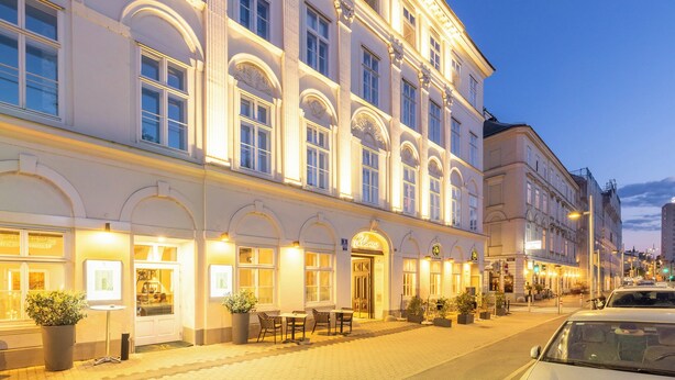 A historic building with arched windows and a ground-floor café with outdoor seating. - Parkview Boutique Apartments (Vienna)