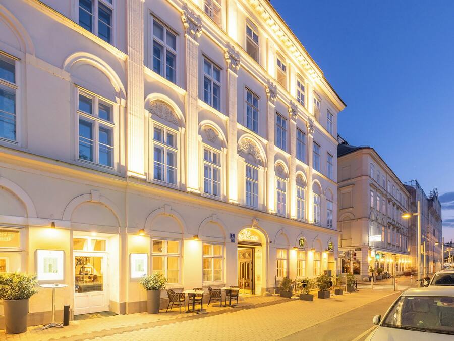 Um edifício histórico com janelas em arco e um café no andar térreo com mesas ao ar livre.