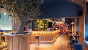 A bar area with a wooden counter, stools, and a tree decoration. - Parkview Boutique Apartments (Vienna)
