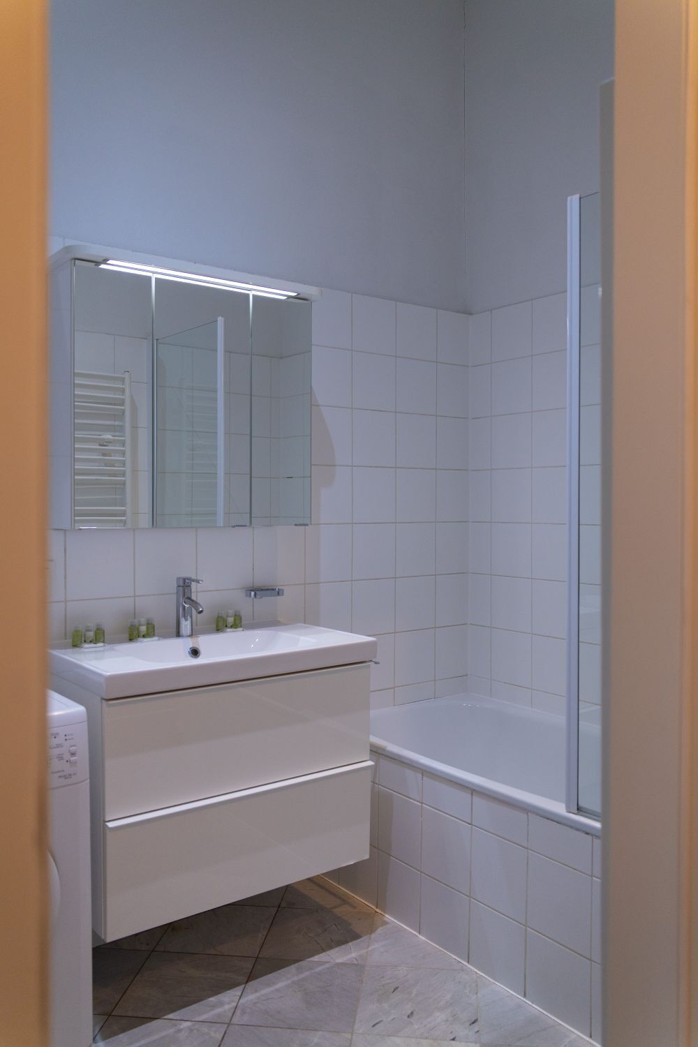 A bathroom with a white sink, mirror, and bathtub.