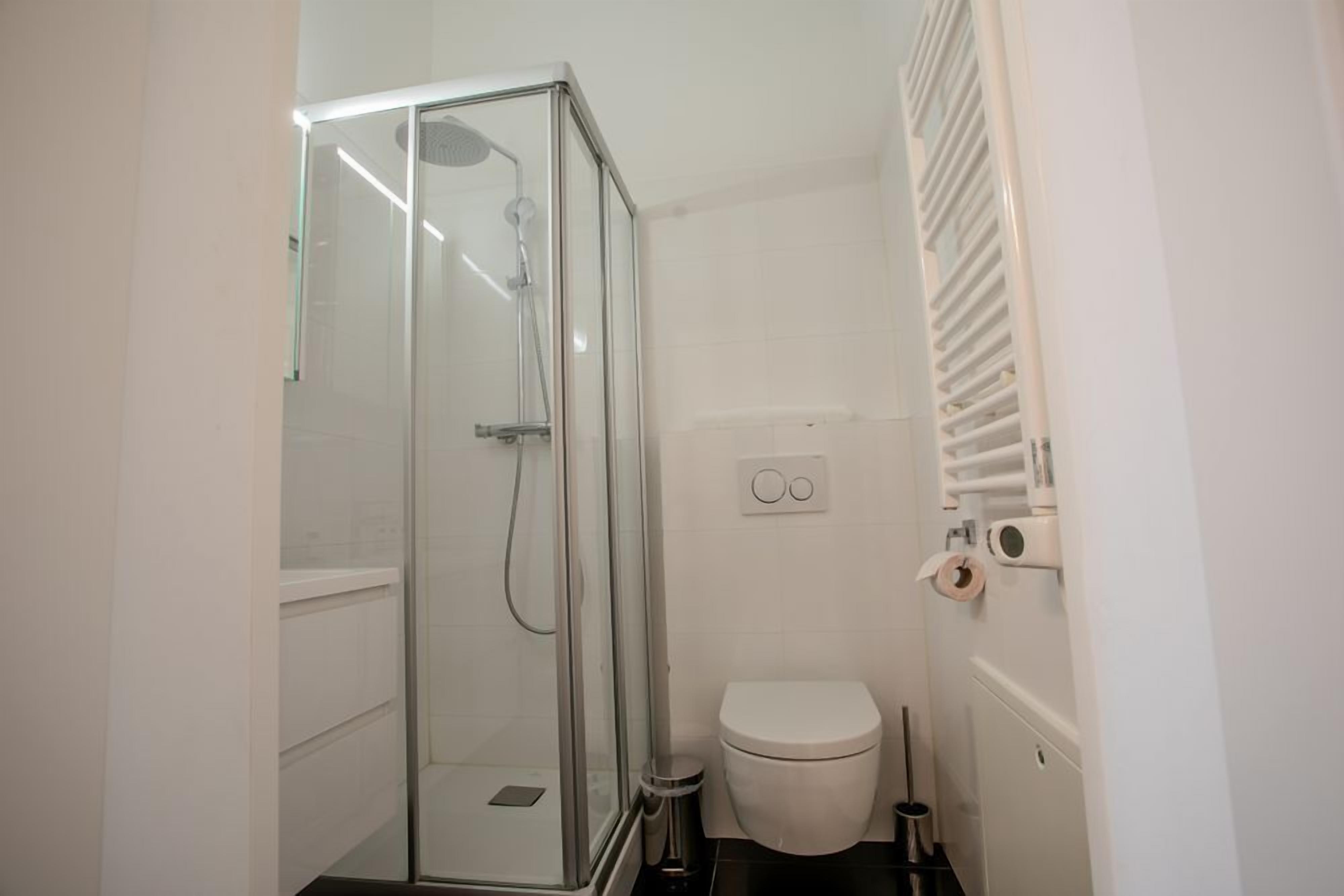 A bathroom with a glass-enclosed shower, a white toilet, and a towel rack.