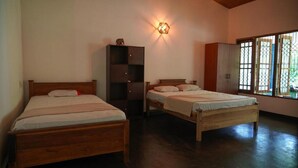 Una habitación con dos camas de madera, un armario y una ventana con barrotes.