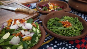 Una mesa con diversos platos en recipientes de barro, incluyendo verduras y especias.