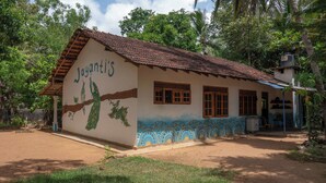 Un pequeño edificio de una sola planta con techo de tejas y un mural de pavos reales en la pared.