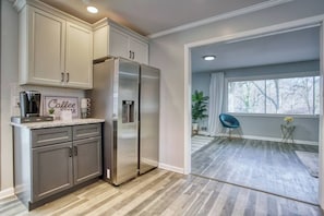 A modern kitchen with stainless steel appliances, a coffee bar, and a view to a balcony with a plant and a chair. - This house is a 3 bedroom(s), 2 bathrooms, located in Decatur, GA. (Decatur)