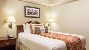 A hotel room with a neatly made bed, two bedside lamps, a framed picture on the wall, and a bedside telephone. - Near Colonial Williamsburg, Busch Gardens, Historic Jamestown (Williamsburg)