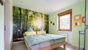 A bedroom with a bed, a window, a radiator, and a wall with a forest mural. - Apartment 'Haus Gertrud' with Mountain View, Shared Terrace, and Wi-Fi (Bühl)