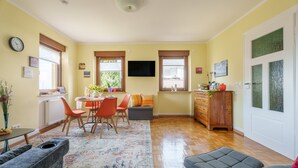 A living room with a dining area, a sofa, a coffee table, a TV, and a door with frosted glass panels. - Apartment 'Haus Gertrud' with Mountain View, Shared Terrace, and Wi-Fi (Bühl)