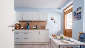 A modern kitchen with white cabinets, a wooden countertop, and a dining area with a table and bench. - Apartment 'Haus Gertrud' with Mountain View, Shared Terrace, and Wi-Fi (Bühl)
