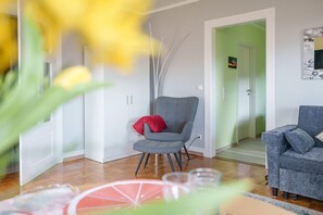 Ein modernes Wohnzimmer mit grauem Sessel, einer Couch und Holzboden.